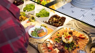 A man picks salad and meat from a buffet.