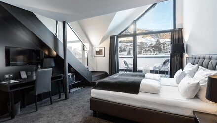 Elegantes Zimmer mit Doppelbett und freiem Blick auf die Berge.