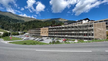Ein modernes Gebäude umgeben von Bergen und Wolken.