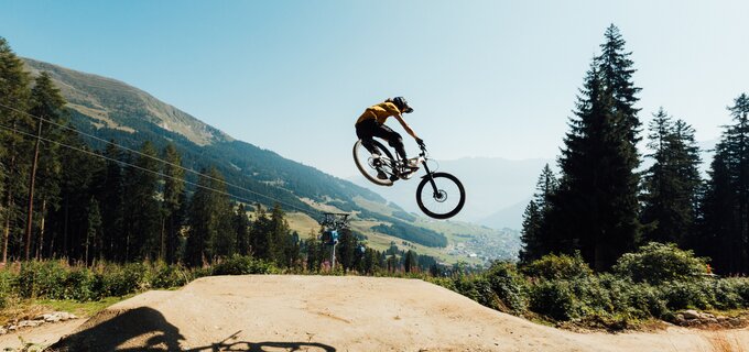 Ein Mountainbiker springt in die Luft über eine Sandrampe.