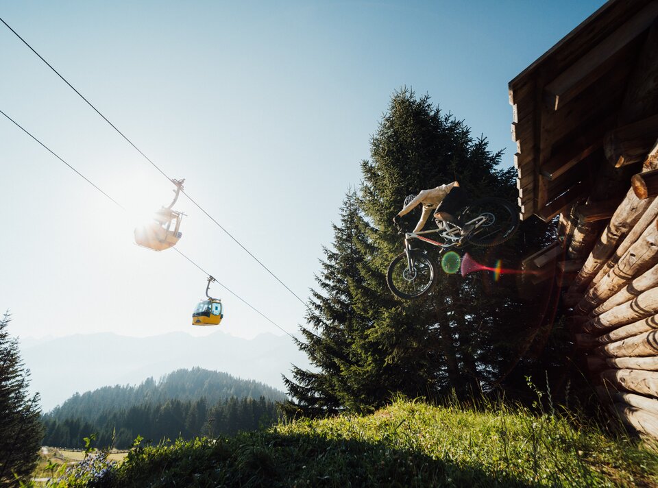 A mountain biker jumps through the air near a lodge.