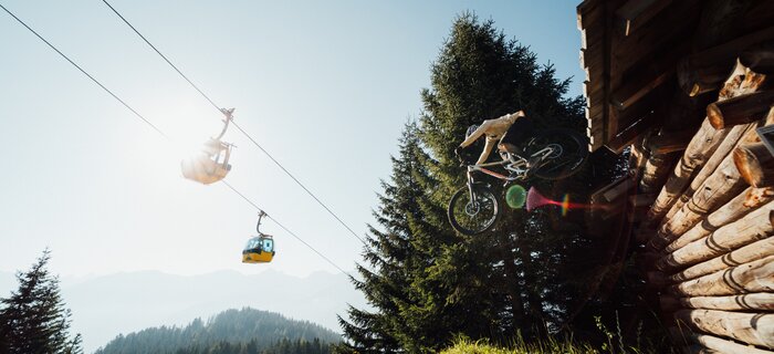 A mountain biker jumps through the air near a lodge.