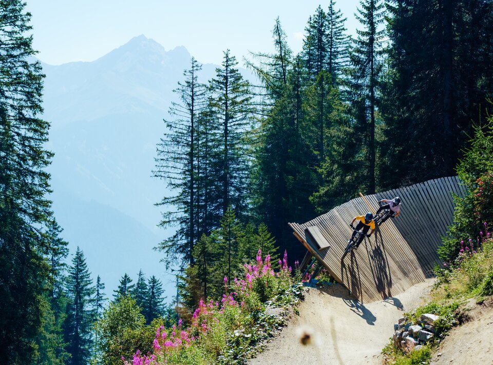 Ein Mountainbiker fährt eine Holzrampe in den Bergen mit Blick auf die Natur.