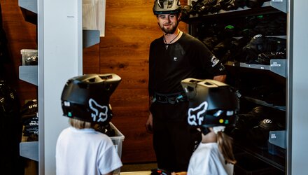 An instructor is talking to two youth in protective gear.