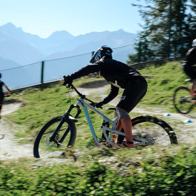Drei Mountainbiker fahren auf einer kurvigen Strecke in den Bergen.