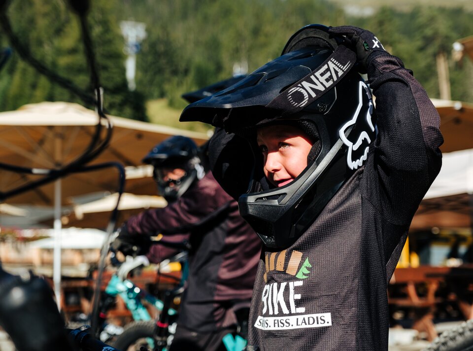 Ein Junge zieht seinen Helm an, bereit für Mountainbiking.