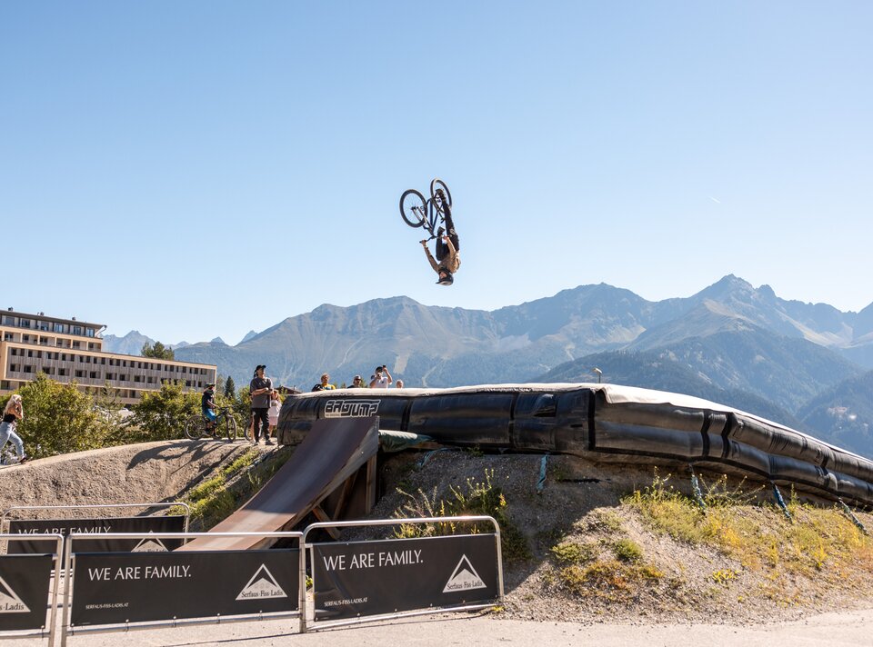 Ein Radfahrer macht einen Rückwärtssalto über eine Sprungrampe in den Alpen.