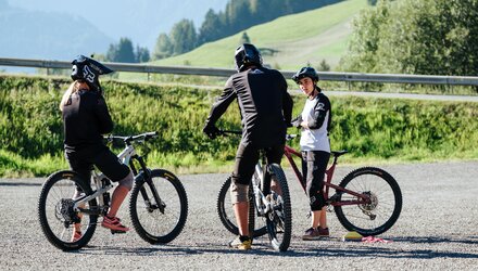 Three mountain bikers are discussing and preparing for their ride.