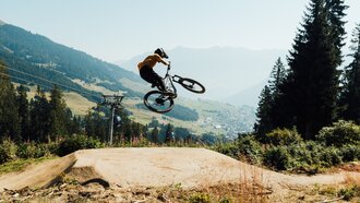 A mountain biker jumps over a hill in the mountains.