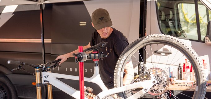 A mechanic works on a mountain bike under a tent.