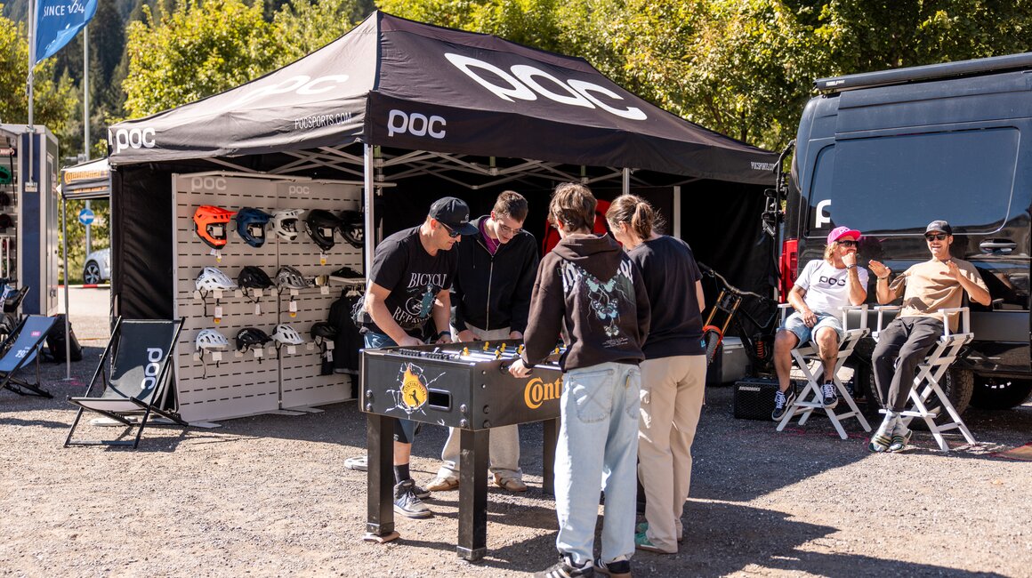 Group of people playing foosball under a tent.