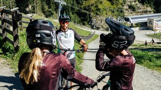 Zwei Mountainbiker mit Helmen, die sich unterhalten.