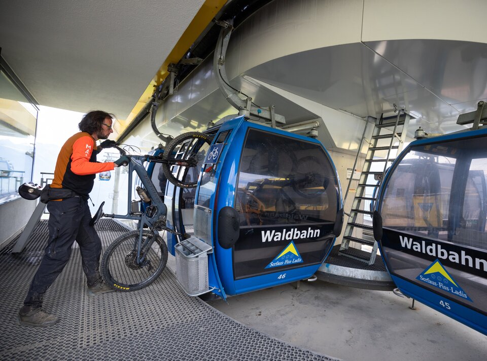 A cyclist loading their bike into a mountain cable car.
