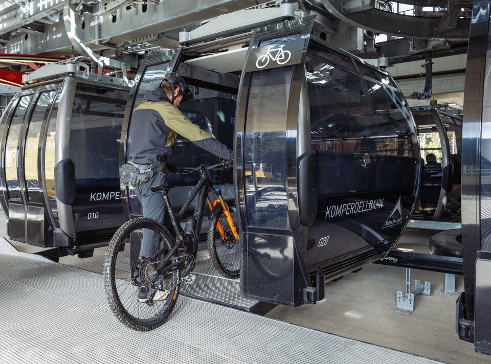 A mountain biker is entering a cable car with his bike.