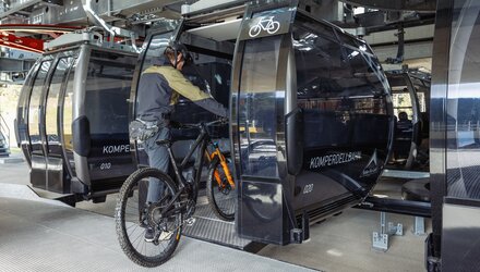 Ein Mountainbiker betritt eine Gondel mit seinem Fahrrad.