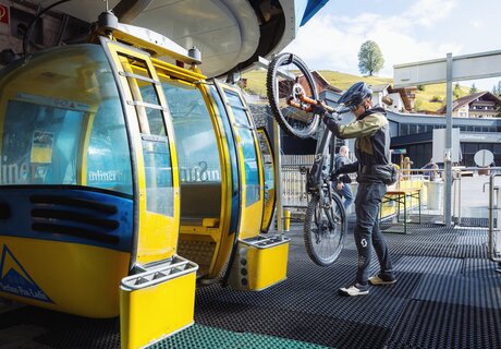 A biker is at the gondola lift with his bike.