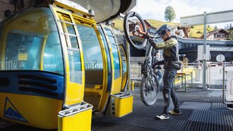 A biker is at the gondola lift with his bike.