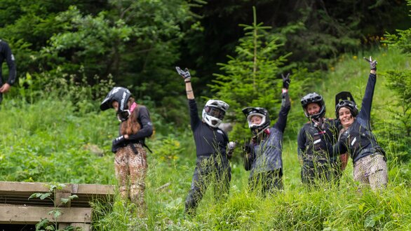 A group of mountain bikers happily posing in the grass.